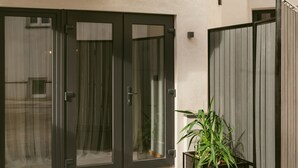 A set of dark-colored doors with glass panels, a potted plant beside them, and a textured wall in the background. - Lwowska City Garage (Warsaw)