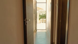 A hallway with a door leading to an outdoor area with potted plants. - Etna Dimora dei Saponari (Trecastagni)