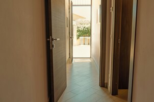 Un corridoio con una porta che dà su un'area esterna con piante in vaso.