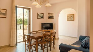 A dining area with a table, chairs, a television, and framed pictures on the wall. - Etna Dimora dei Saponari (Trecastagni)