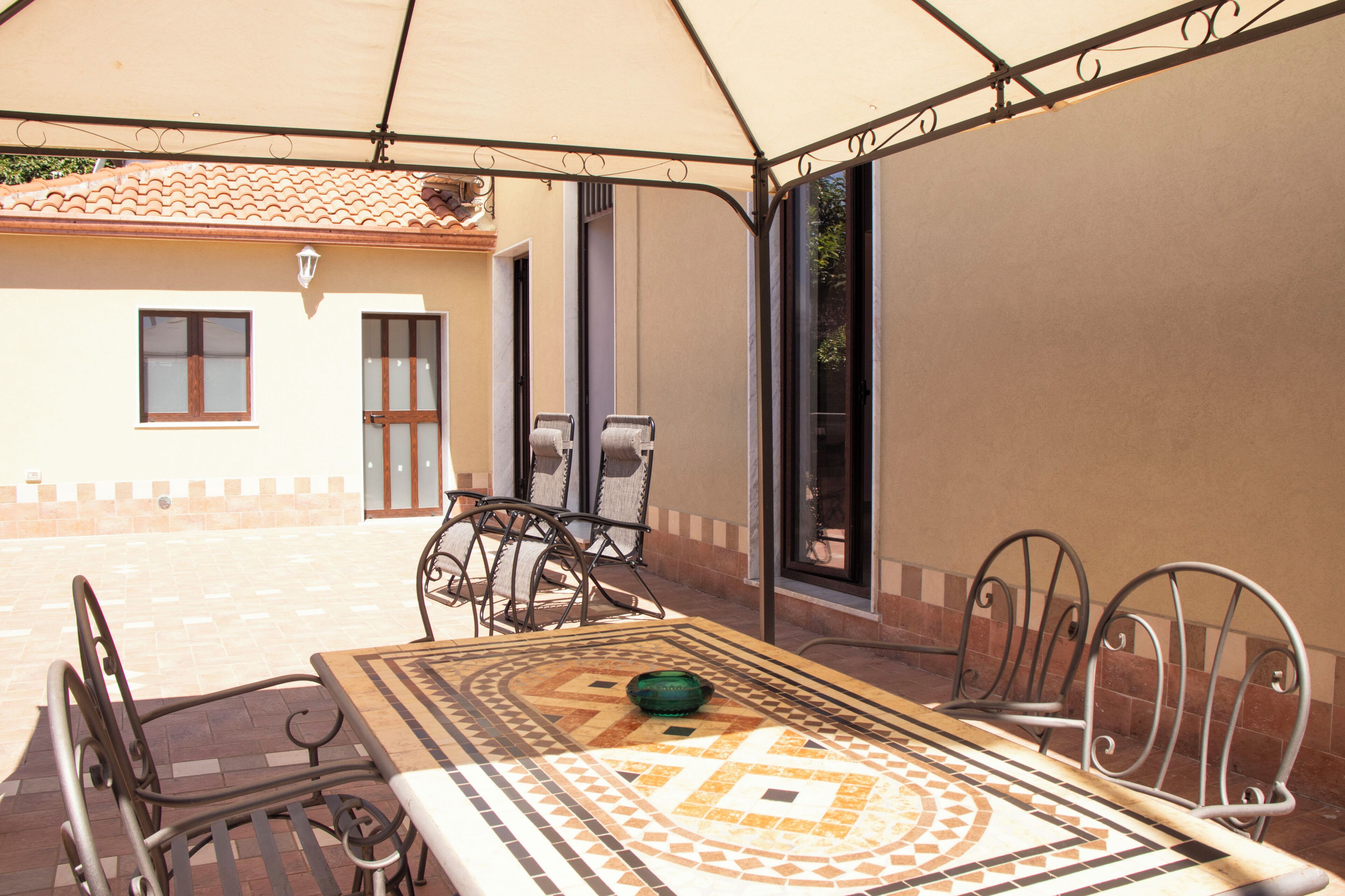 Une terrasse extérieure avec une table, des chaises et un espace abrité.