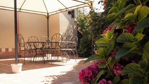 An outdoor patio with a table and chairs, surrounded by potted plants and flowers. - Etna Dimora dei Saponari (Trecastagni)