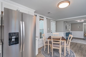 A modern kitchen with a built-in refrigerator, a water dispenser, and a dining area with a round table and chairs. - Cozy home with firepit-minutes from downtown and the University of SC!  (West Columbia)