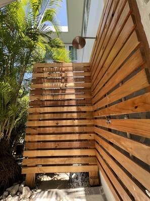 Une pergola en bois agrémentée d’un élément aquatique, entourée d’une végétation luxuriante.