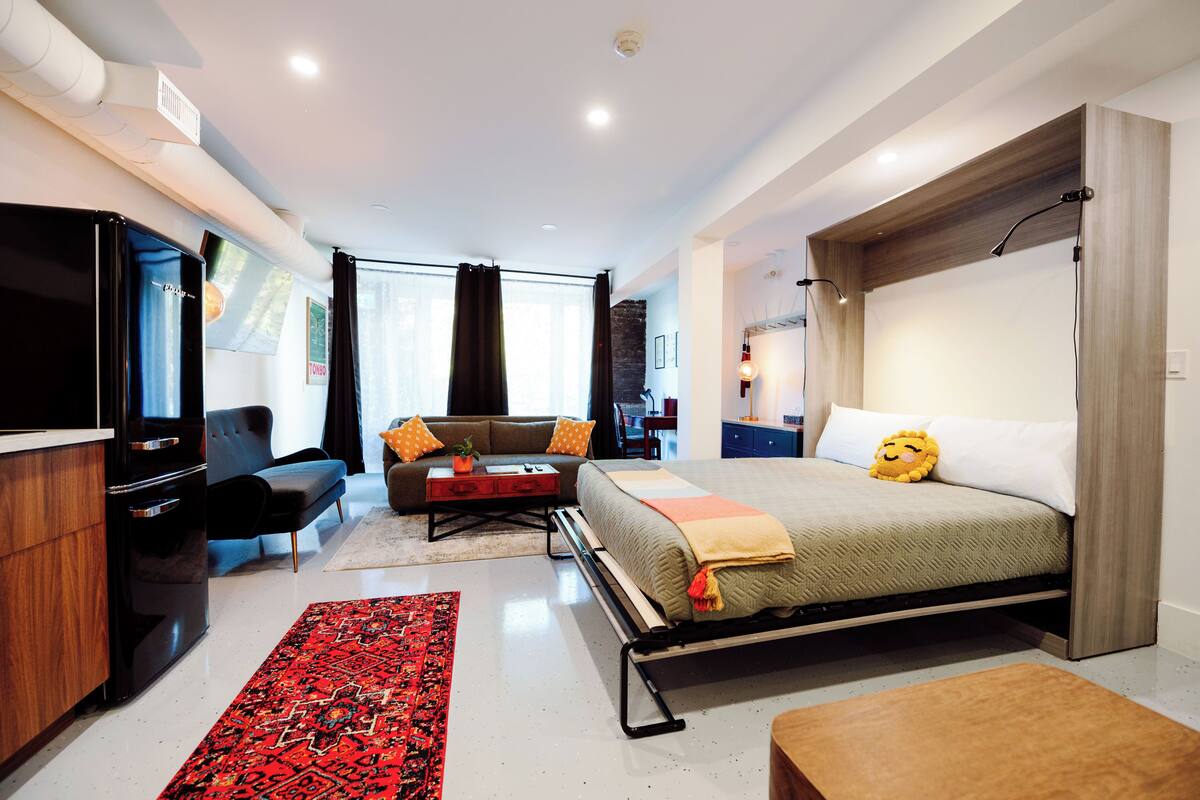 A modern bedroom with a bed, a sofa, a TV, and a desk.