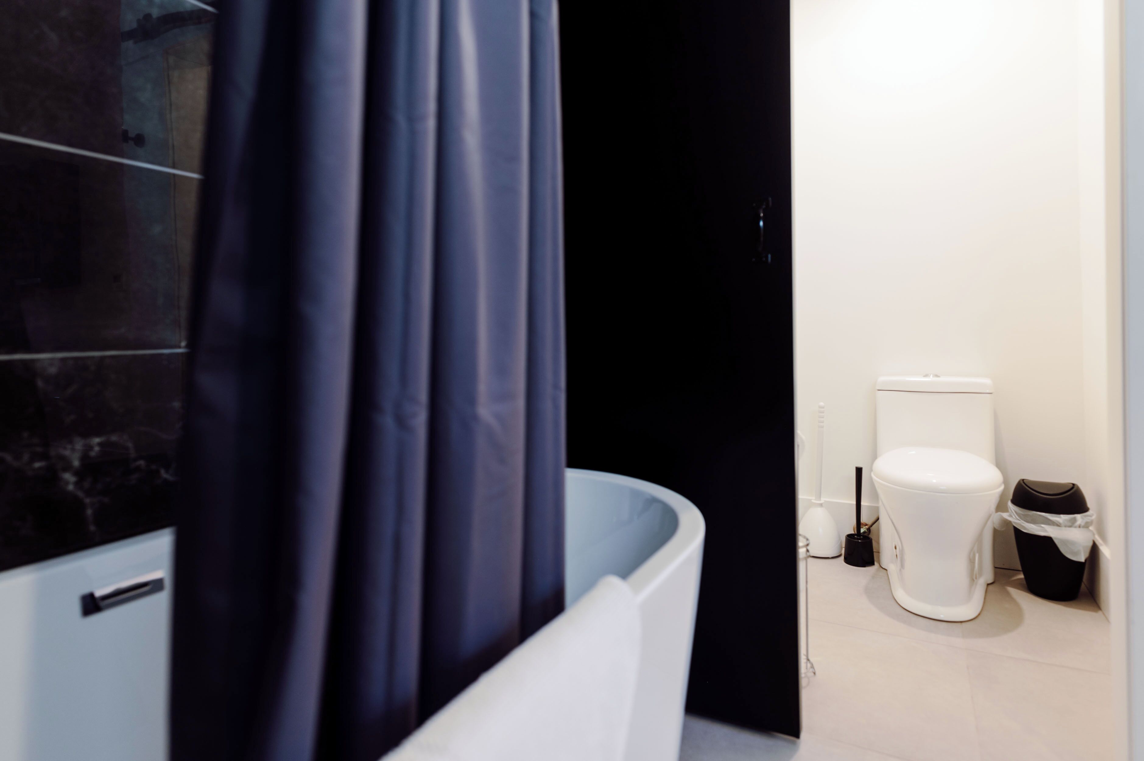 Ein Badezimmer mit Badewanne, Toilette und Mülleimer.