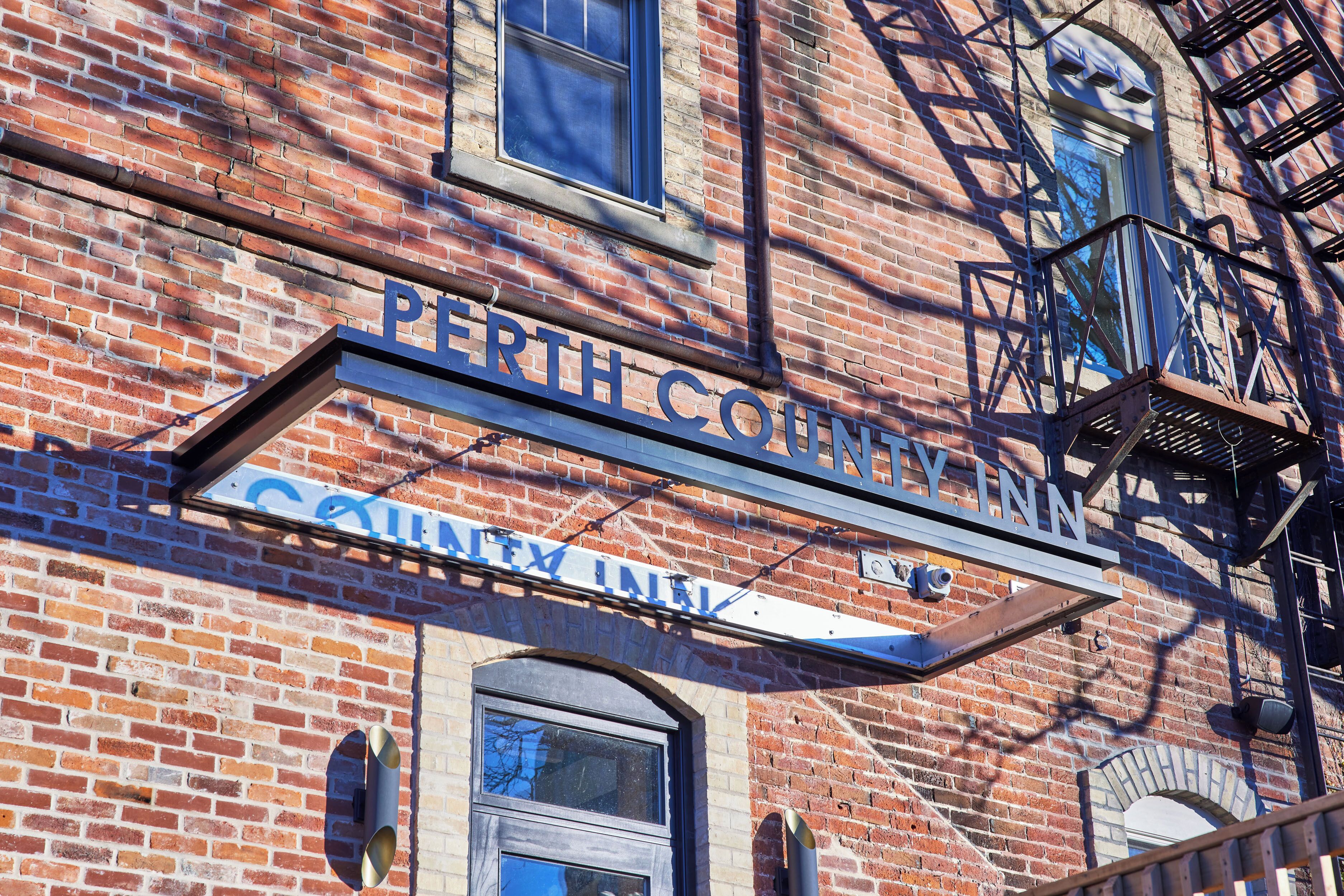 A brick building with a sign that reads "Perth County Inn."