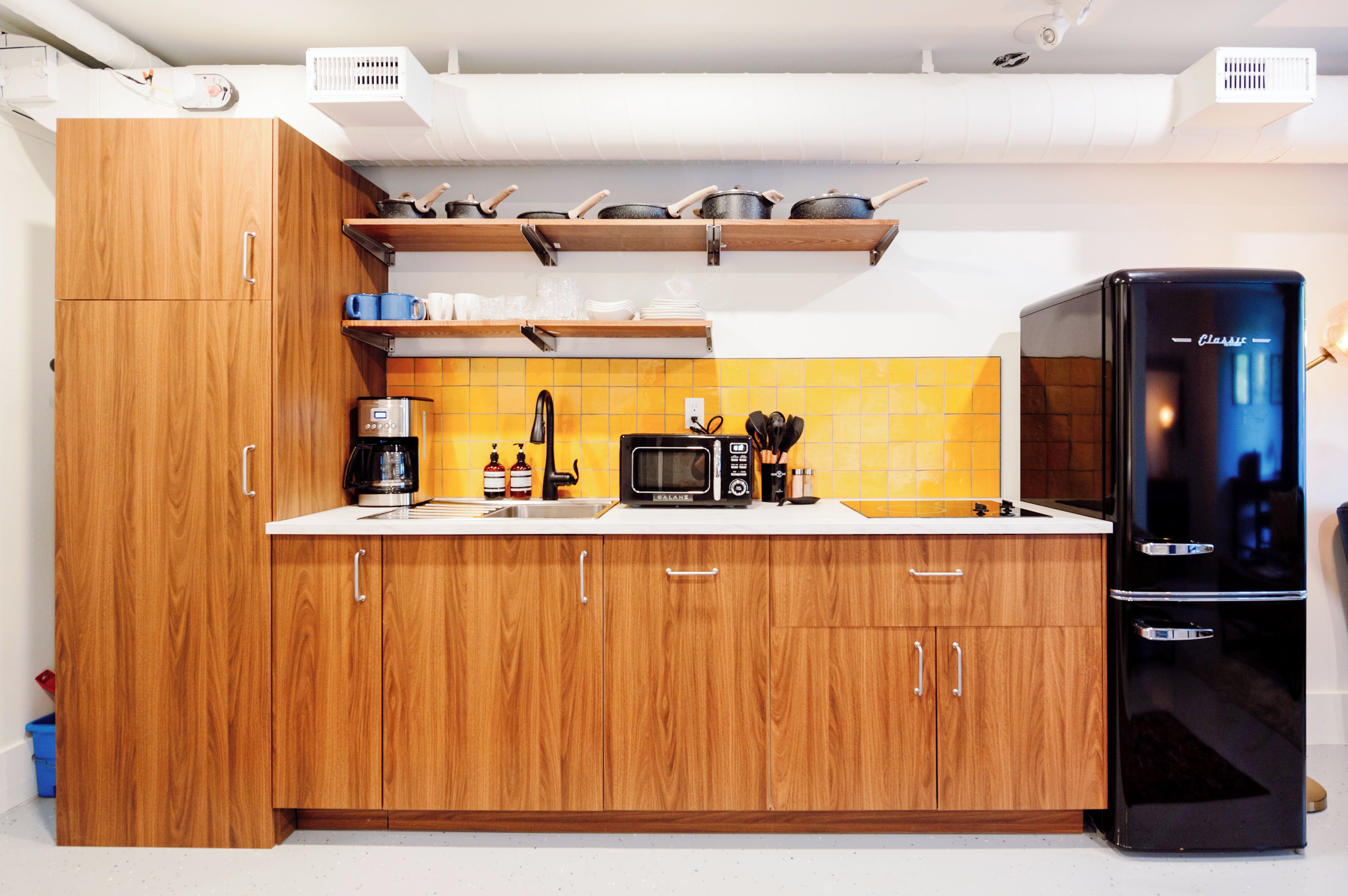 Una cucina moderna con mobili in legno, un frigorifero nero, un forno a microonde e una macchina da caffè.