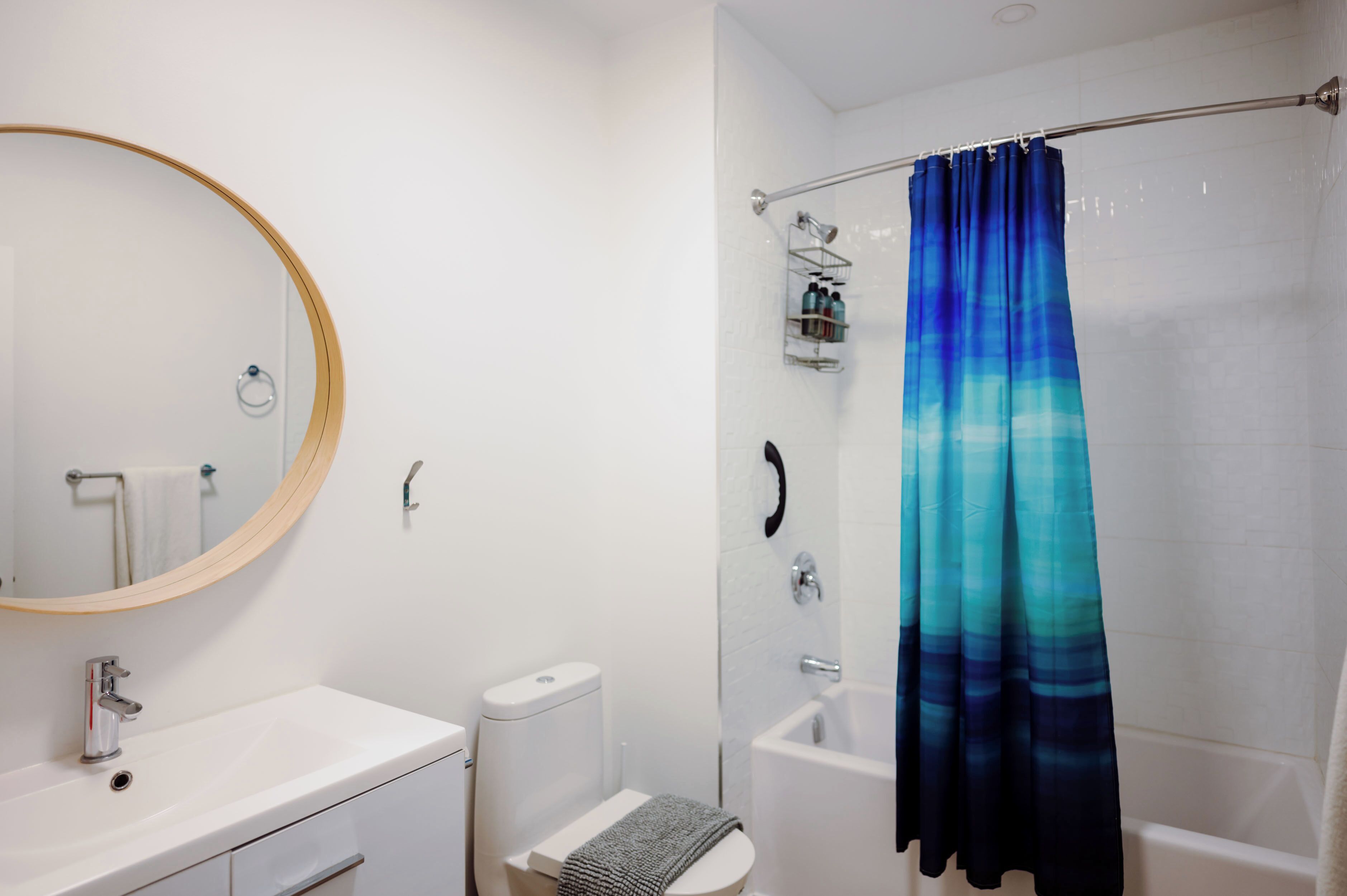 A bathroom with a white sink, toilet, and bathtub. There is a shower curtain and a mirror above the sink.