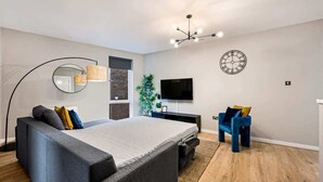 A modern bedroom with a large bed, a TV, a clock, and a unique ceiling light fixture. - Host & Stay | Ropewalks Quarters II (Liverpool)