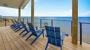 A wooden deck with blue chairs and a view of the ocean. - Premier Soundfront w/ Pool, Hot Tub, Elevator, EV Charger, Pickleball, Theater (Rodanthe)