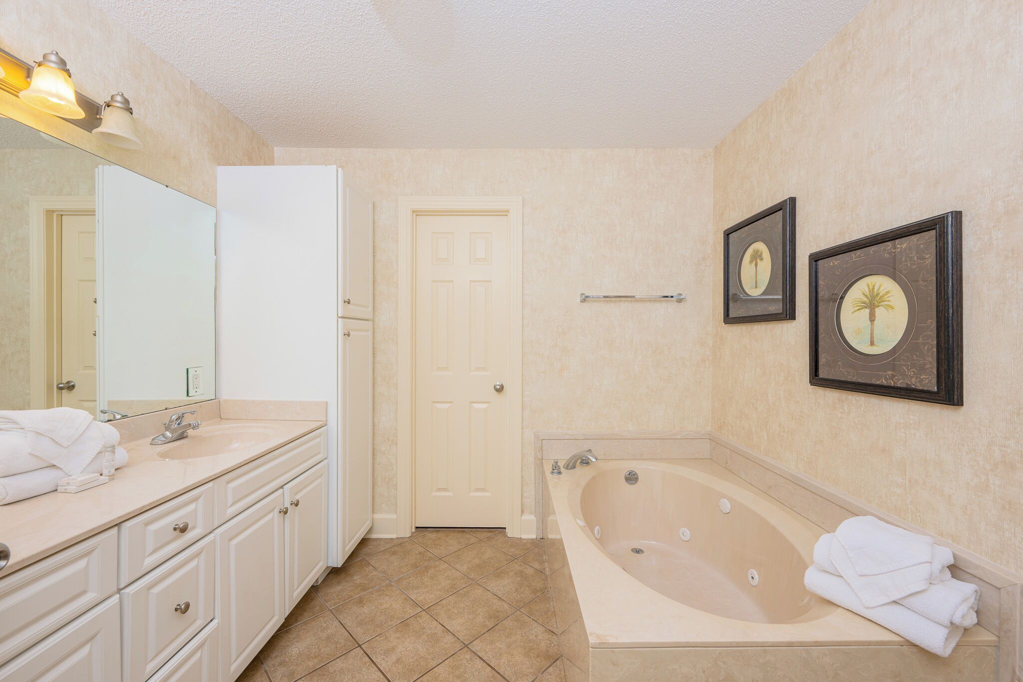 Un bagno con una vasca da bagno ampia, un lavabo con specchio e due quadri appesi al muro.