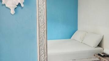 A room with a bed, a decorative mirror, and a wall-mounted light fixture.