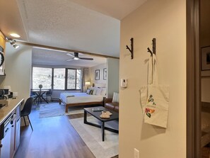 A hotel room with a bed, a desk, a chair, a coffee table, and a view of a snowy landscape through the window.