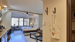 Een hotelkamer met een bed, een bureau, een stoel, een salontafel en uitzicht op een besneeerd landschap door het raam.