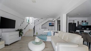 A modern living room with a white sofa, a coffee table, and a TV mounted on the wall. - Seafront Villa Azzurro with heated pool, panoramic sea views, walking distance to beach-shop-restaurant (Stanici)