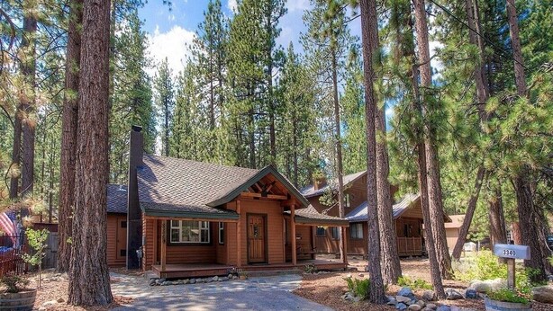 A cabin with a porch, surrounded by tall pine trees. - Breezy Pines Cabin 4 Bedroom Home by RedAwning (South Lake Tahoe)