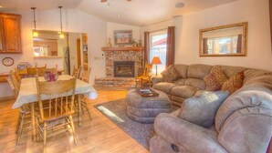 A cozy living room with a fireplace, a dining table with chairs, and a comfortable sofa. - Breezy Pines Cabin 4 Bedroom Home by RedAwning (South Lake Tahoe)
