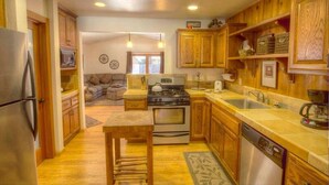 A compact kitchen with wooden cabinets, stainless steel appliances, and a central island. - Breezy Pines Cabin 4 Bedroom Home by RedAwning (South Lake Tahoe)