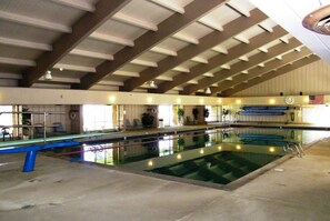 An indoor swimming pool with a high ceiling and a long, narrow shape.