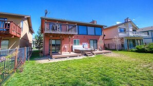 A two-story house with a patio, a hot tub, and a fenced yard.
