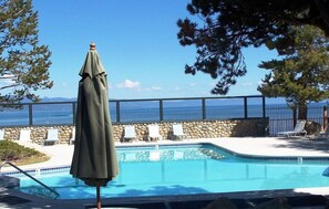 Ein Pool mit Steinmauer und Liegestühlen mit Blick auf ein Gewässer.