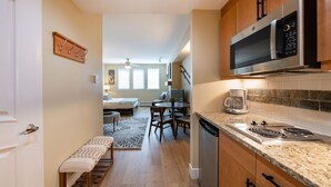 Une cuisine moderne équipée d’un four à micro-ondes, d’une cuisinière et d’un lave-vaisselle intégrés. On y trouve un coin repas avec une table et des chaises, ainsi qu’un banc le long du couloir.