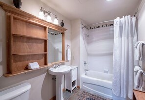 Een badkamer met een wastafel, spiegel, wastafelmeubel en een bad.
