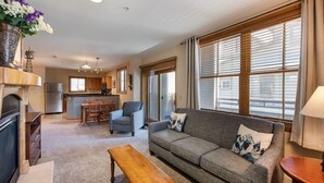 A living room with a sofa, a coffee table, and a dining area with a table and chairs. - Premium Unit 1327 - One Bedroom - Zephyr Mountain Lodge 1 Condo (Winter Park)