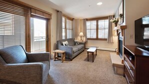 A living room with a sofa, a coffee table, a TV, and a fireplace. - Premium Unit 1327 - One Bedroom - Zephyr Mountain Lodge 1 Condo (Winter Park)