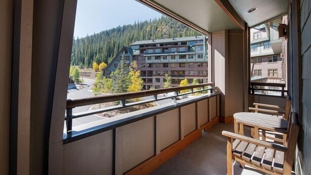 A balcony with a view of a multi-story building and a forested hill. - Premium Unit 1327 - One Bedroom - Zephyr Mountain Lodge 1 Condo (Winter Park)