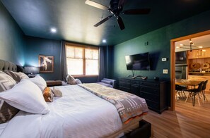 A bedroom with a bed, a dresser, a TV, and a view of the kitchen. - Premium Unit 1403 - Two Bedroom - Zephyr Mountain Lodge 2 Condo (Winter Park)