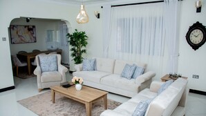 Ein modernes Wohnzimmer mit einer Sofagarnitur, einem Couchtisch und einem Essbereich mit einer Pendelleuchte.