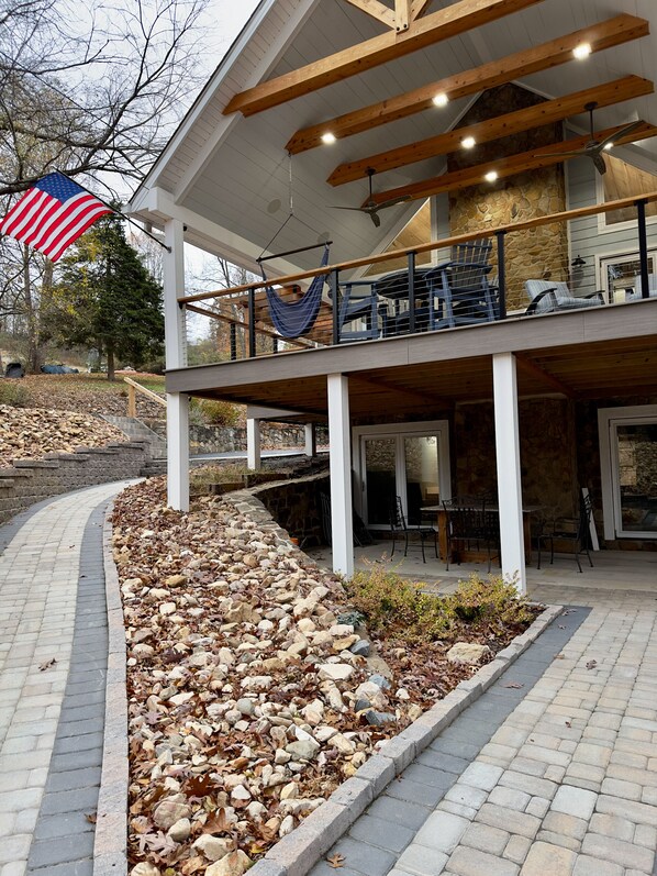 A covered outdoor area with a stone wall, a wooden deck, and a seating area with chairs and a table.