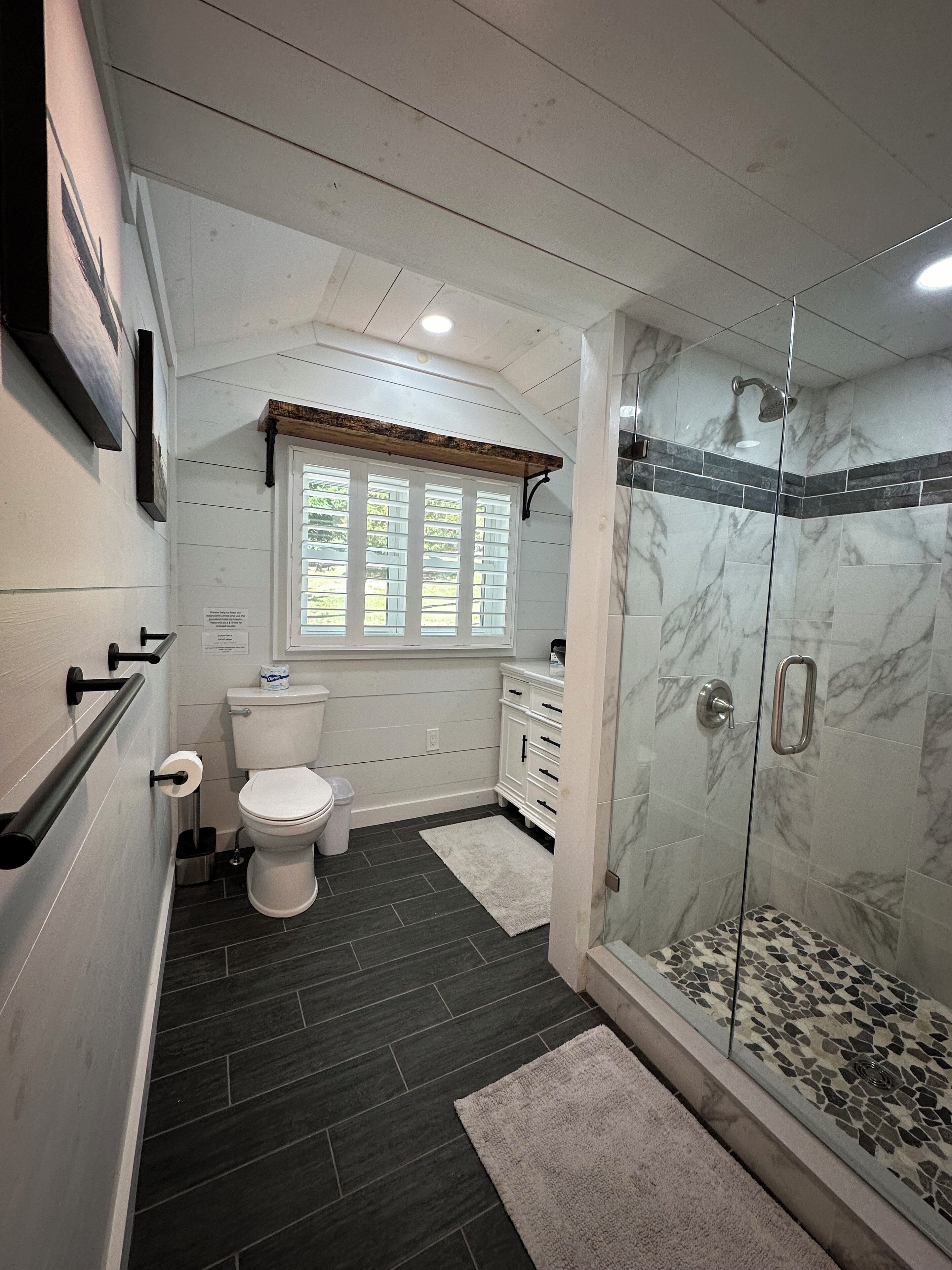 A bathroom with a toilet, a sink, a shower, and a window.