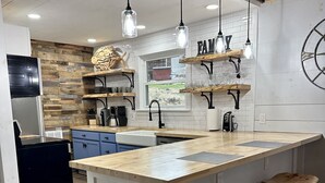A modern kitchen with a large island, wooden accents, and pendant lighting.