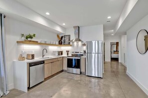 Una cocina moderna con armarios blancos, electrodomésticos de acero inoxidable y una isla central.