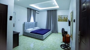Une chambre à coucher avec un lit, un ventilateur de plafond et une fenêtre avec des rideaux.