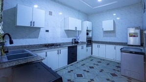 Une cuisine moderne avec des meubles blancs, une cuisinière à gaz, un four à micro-ondes et un réfrigérateur.