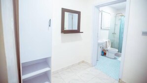 A bathroom with a shower, toilet, and a mirror on the wall.