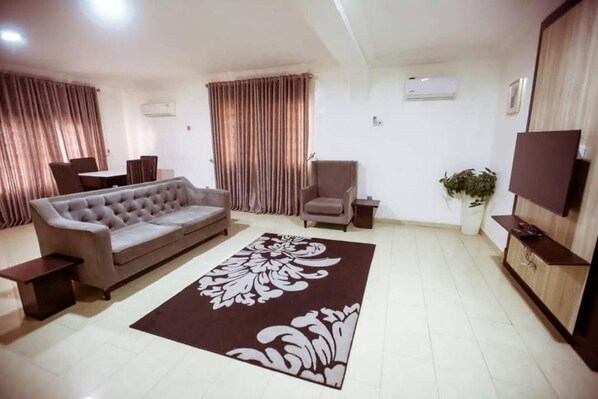 A living room with a sofa, a chair, a TV, and a decorative rug. - Stunning 2-bed Apartment in Lagos (Lagos)