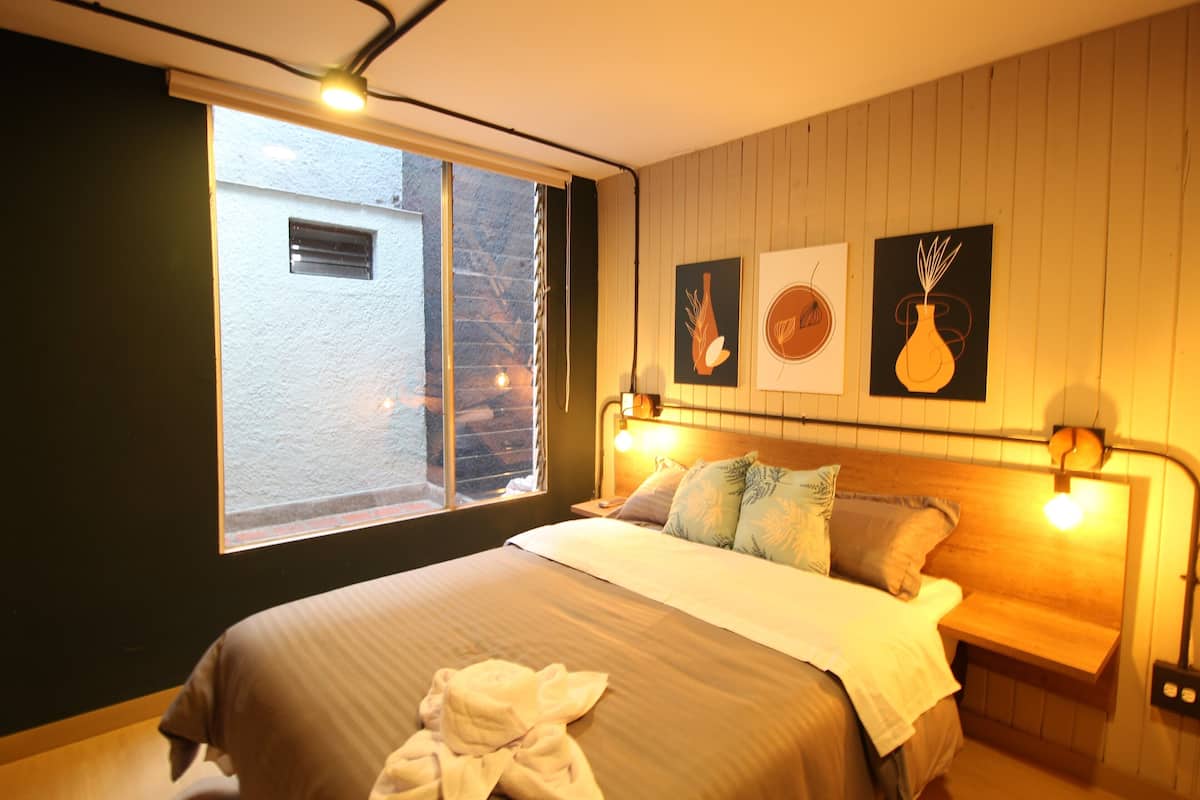 Une chambre avec un grand lit, une fenêtre et des œuvres d’art murales.