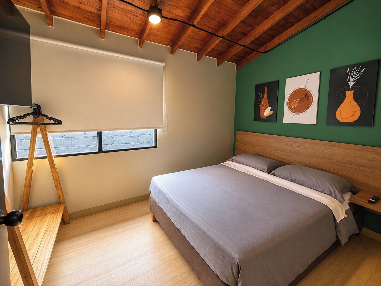 Een slaapkamer met een bed, houten vloer, een raam met uitzicht en kunst aan de muur.