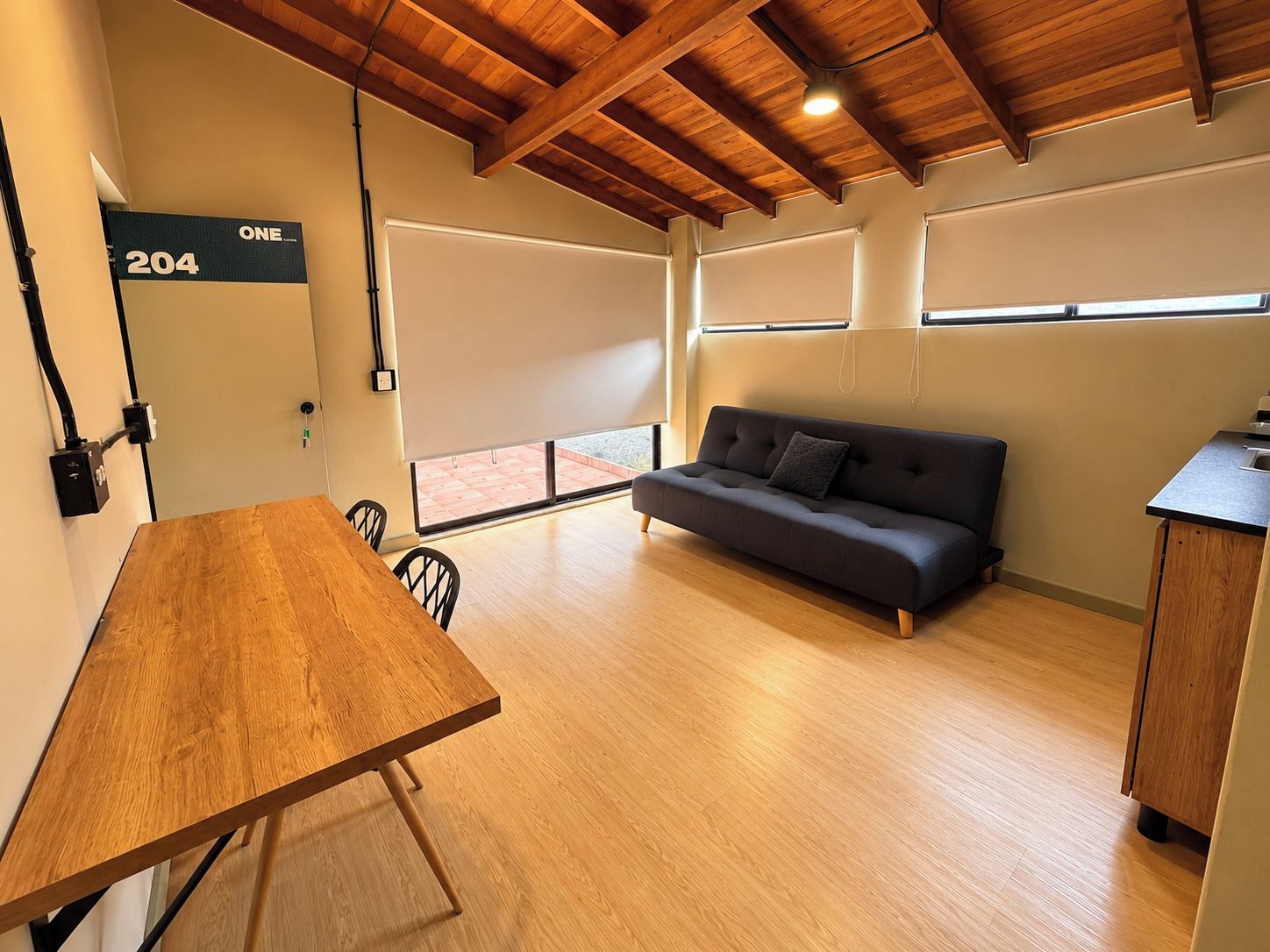 Un interior moderno con una mesa de madera, un sofá y una zona de cocina.