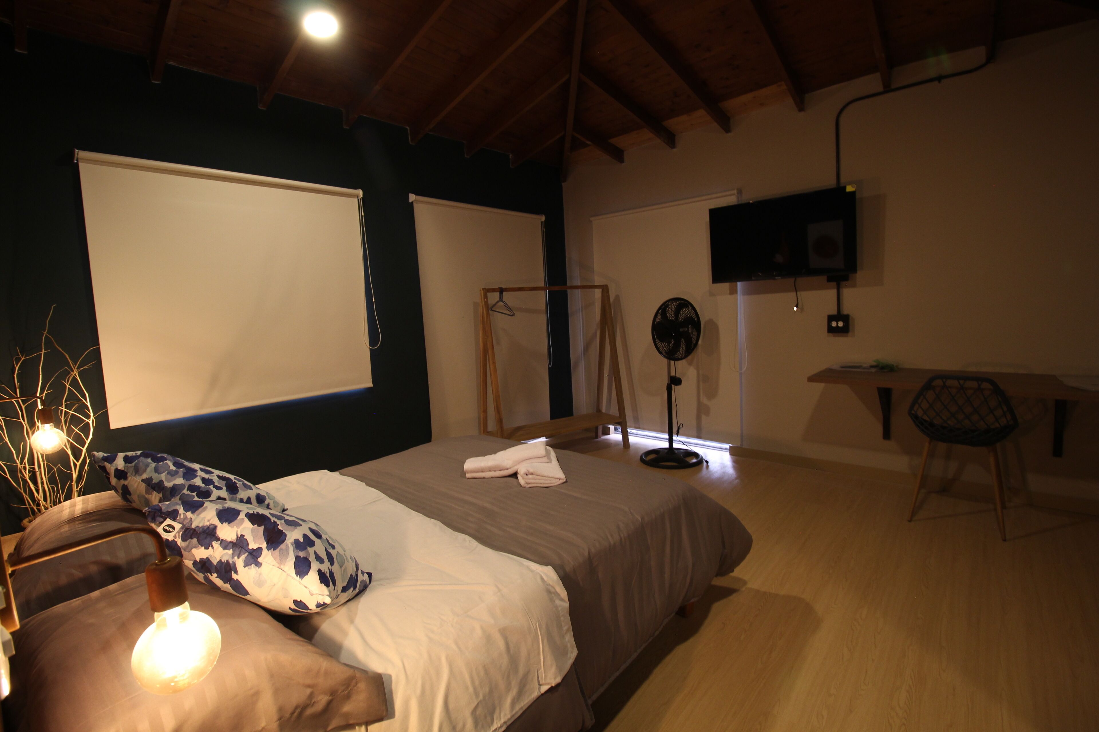 Une chambre à coucher avec un lit, une table de chevet et un téléviseur fixé au mur.