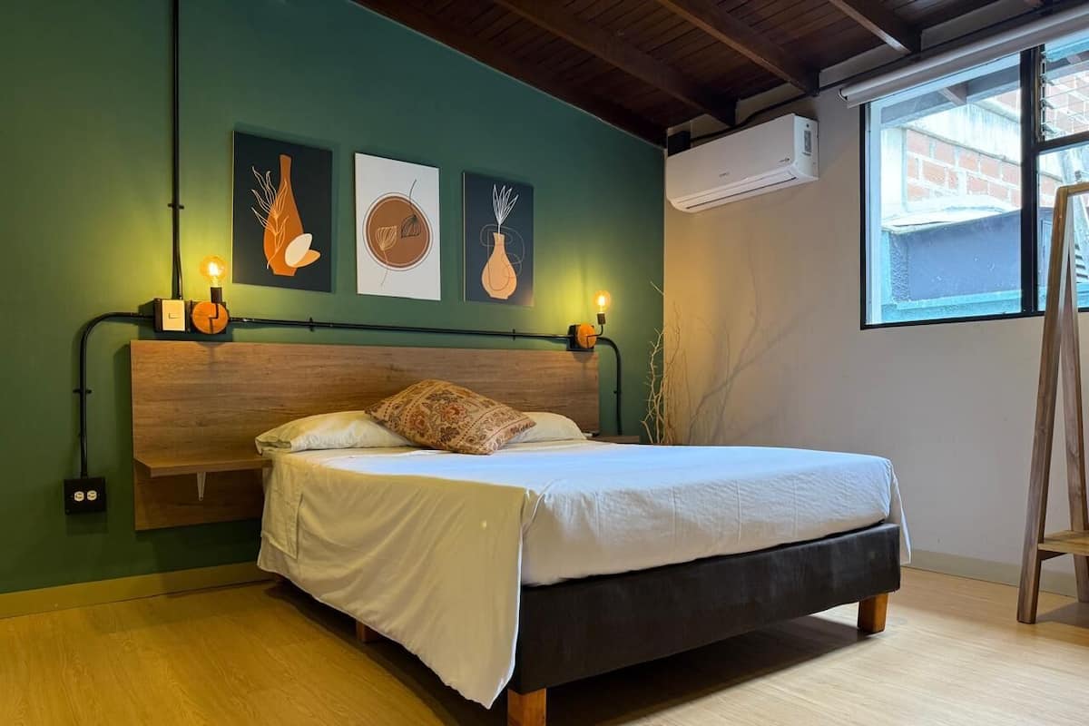 Une chambre à coucher avec une tête de lit en bois, un lit avec une literie blanche et trois appliques murales.