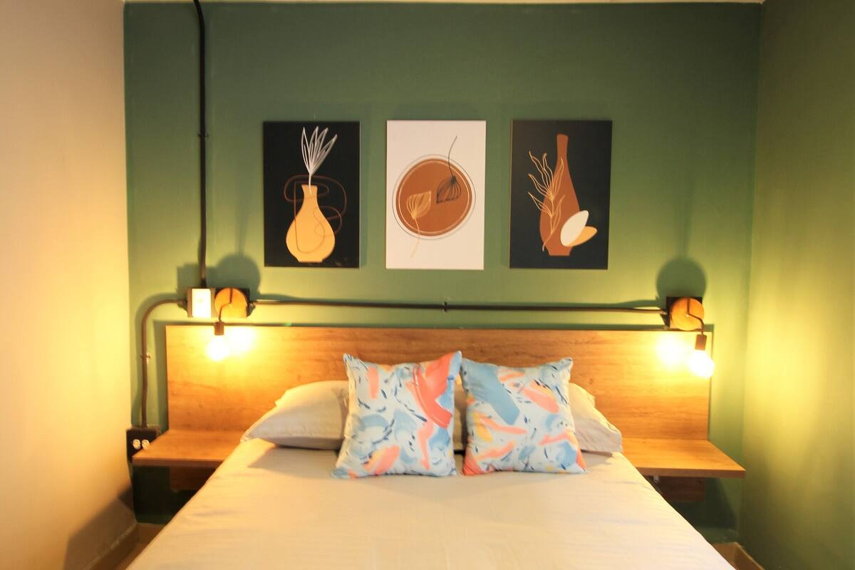 Une chambre d’hôtel avec un lit, deux tables de chevet et des lampes fixées au mur.