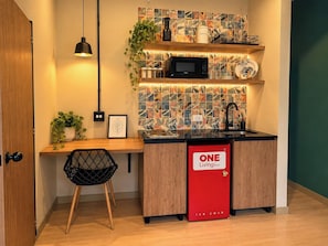 Cuina compacta amb microones, rentapelats i nevera vermella amb el text 'ONE Living Roots'.