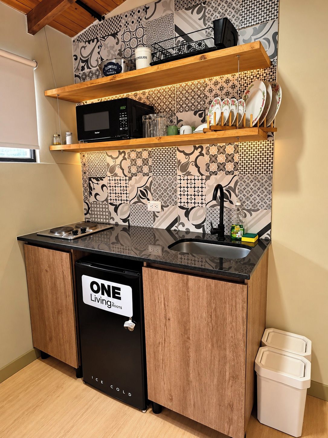 Una cucina compatta con lavastoviglie nera, mobili in legno e piastrelle decorate a parete.