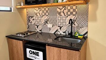 Una cucina compatta con lavastoviglie nera, mobili in legno e piastrelle decorate a parete.
